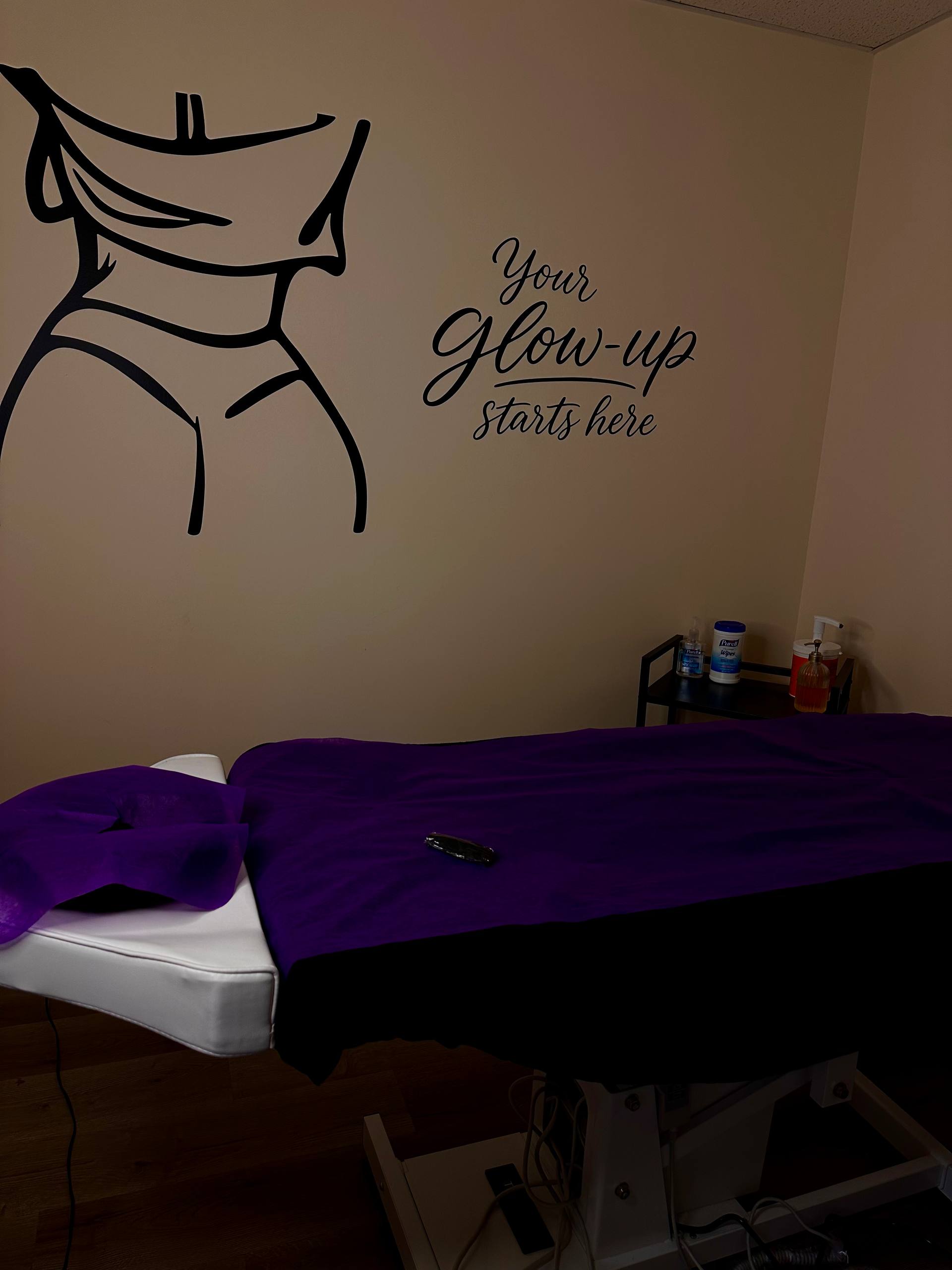 Sculpt & Glow treatment room featuring the studio's signature body-contour wall art and 'Your Glow-Up Starts Here' lettering